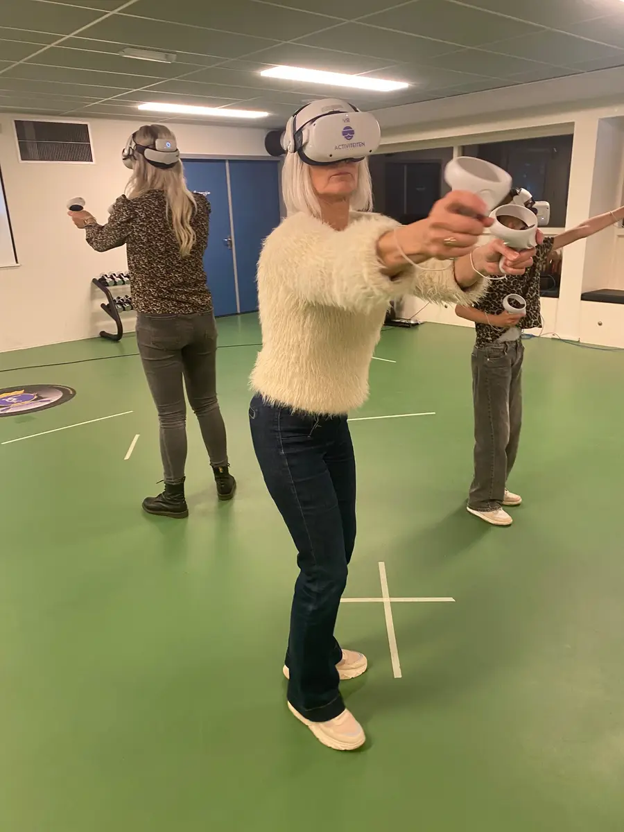 Speelster met VR-bril in actie in een sporthal, andere spelers op de achtergrond