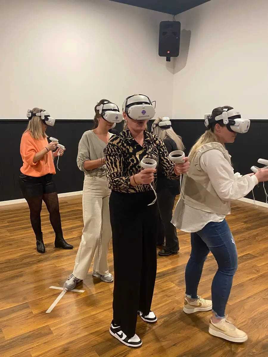 Groep spelers met VR-brillen dicht bij elkaar in een zaal met houten vloer